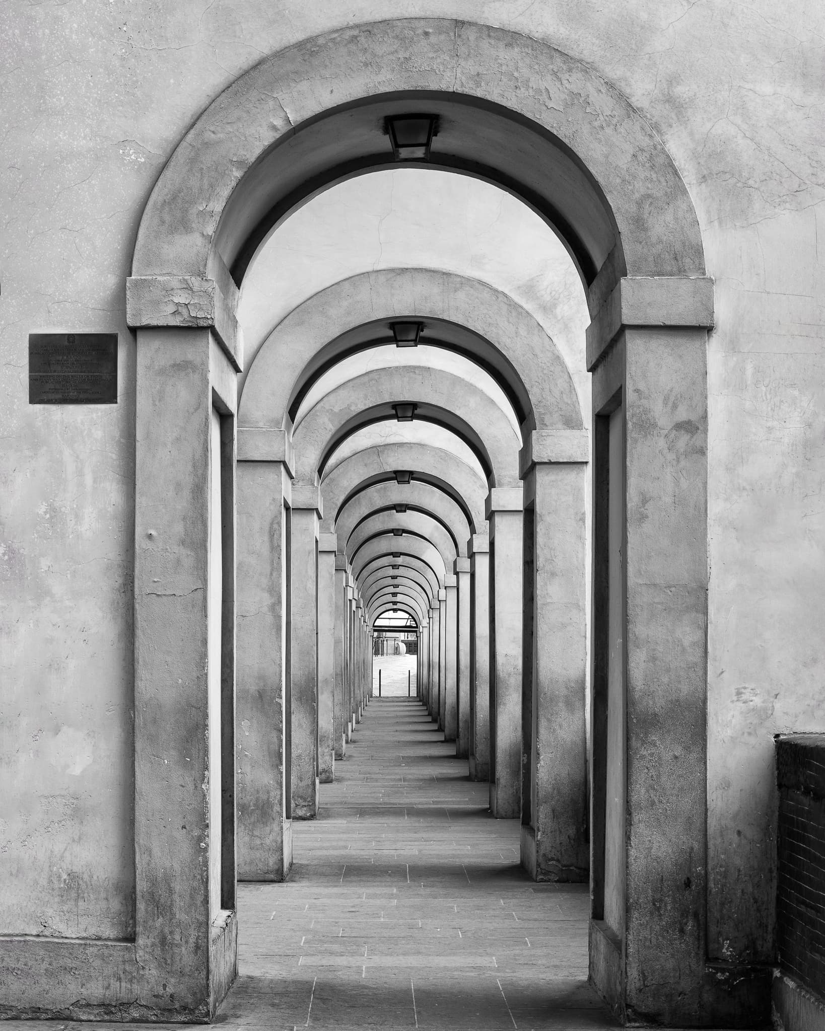 A stone archway in Florence, Italy, framing a walkway through the historic center at night, International. Photograph by Marty Quinn