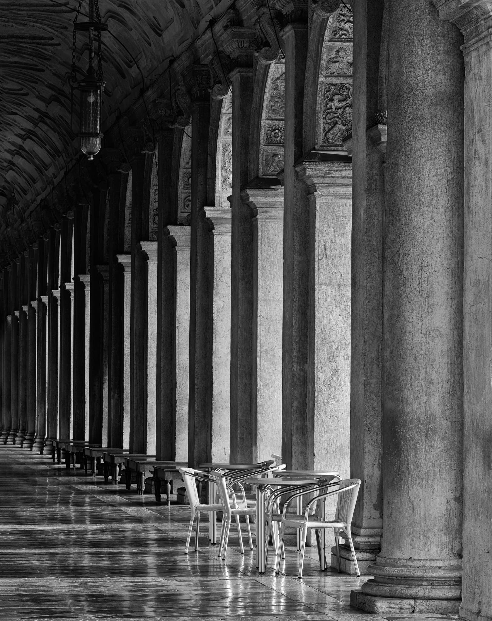 Stone arches and a small table in a quiet corner of Venice, Italy — the city's architecture away from the tourist routes, at night, International. Photograph by Marty Quinn