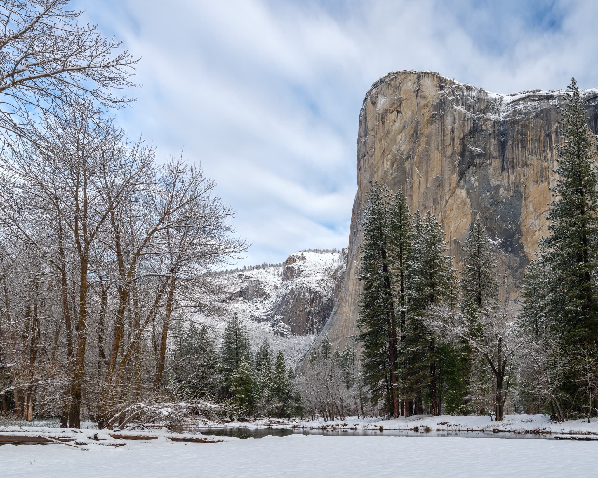 El Capitan from Yosemite Valley on a winter morning, the granite wall rising 3,000 feet against streaking clouds, the Merced River at the base, California. Photograph by Marty Quinn